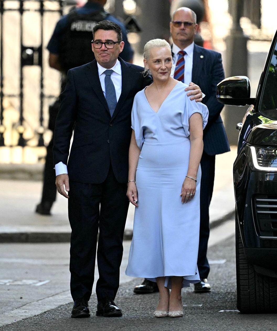 The couple walk arm in arm outside no 10 in front of security, he wears a suit and her a blue dress.