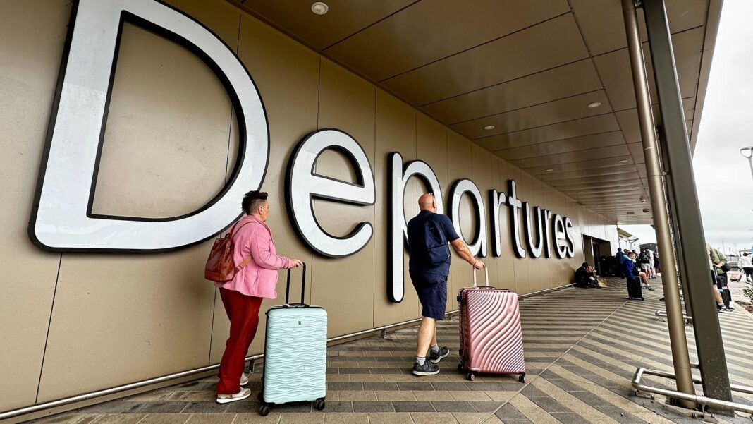 Repeated air traffic control failures leave us in worrying territory A man and a woman roll pink and blue suitcases past a large "Departures" sign at Belfast airport.