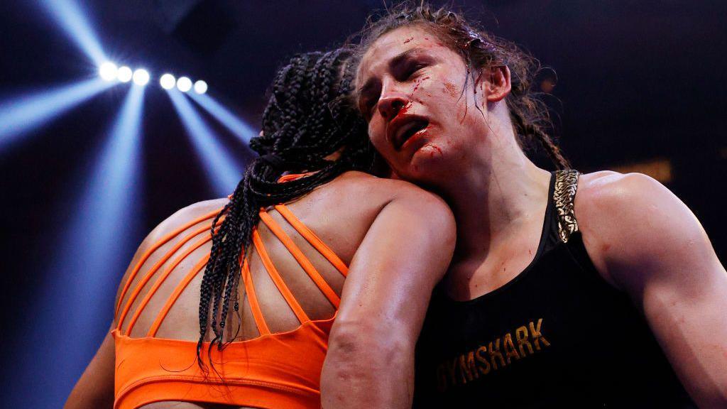 A bloodied Katie Taylor rests her head on Amanda Serrano's shoulder