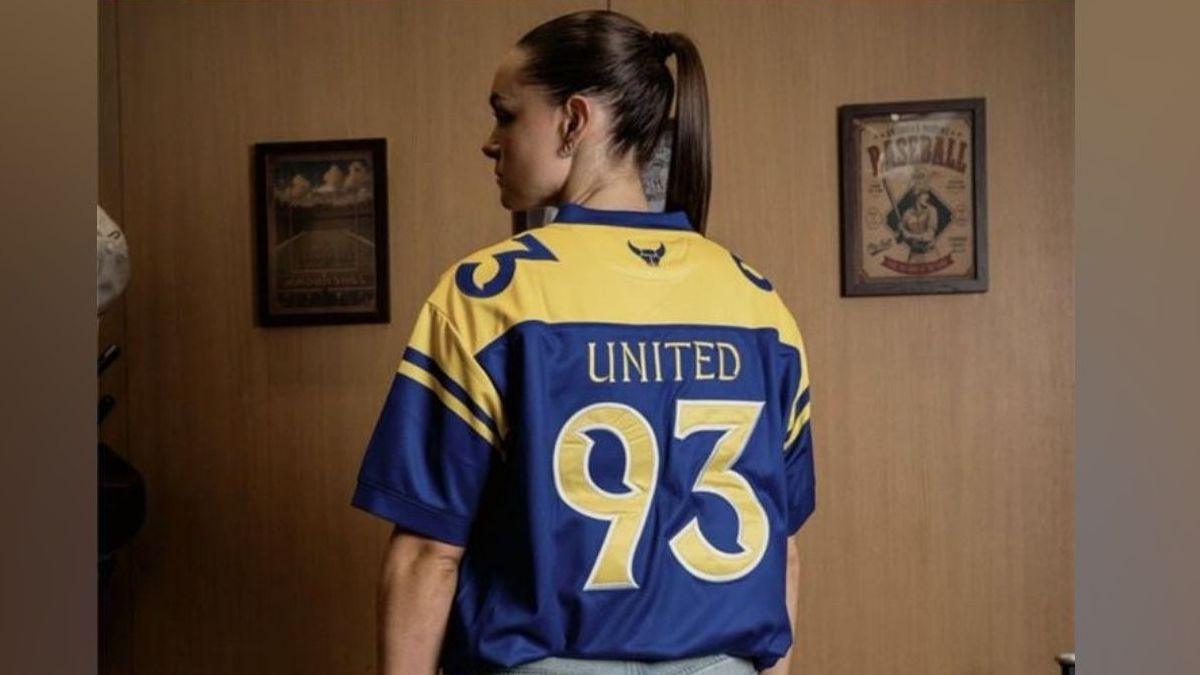 Female model wearing a yellow and blue shirt with "United 93" on the back