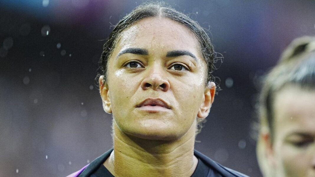 Racist message to England footballer Jess Carter denied by teen Jess Carter, who has her dark hair in a ponytail, wearing a warm-up top ahead of a football match on a rainy day.