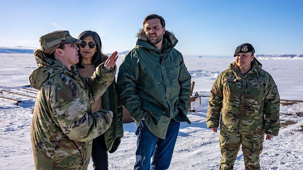 JD Vance and his wife Usha Vance pictured with the commander of the US military's Pituffik Space Base in Greenland in March. They are surrounded by a snowy landscape.