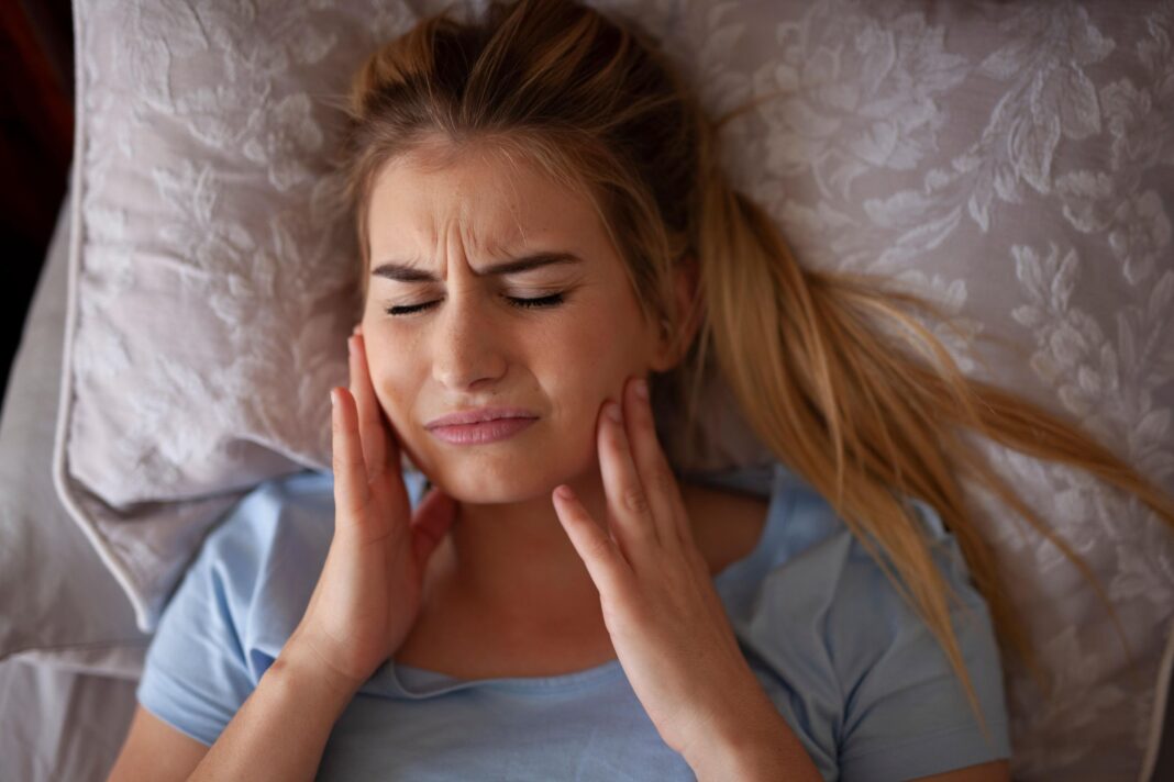Some dentists say more young people are grinding their teeth – are you one of them? Jaw pain after waking up or sleeping - Bruxisum, teeth grinding - stock photo