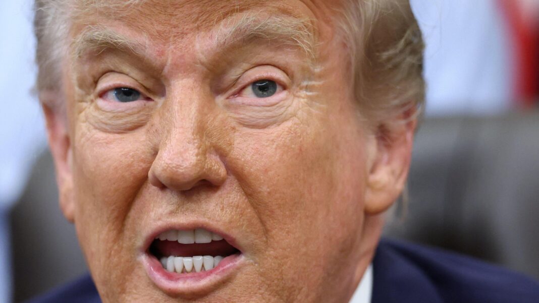 US President Donald Trump has his mouth open in a close up shot. His eyebrows are raised and he is wearing a blue suit jacket.