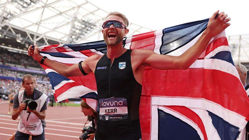 Josh Kerr celebrates while draped in a Union Jack after setting a new world record in the men's mile at the Diamond League meeting in London