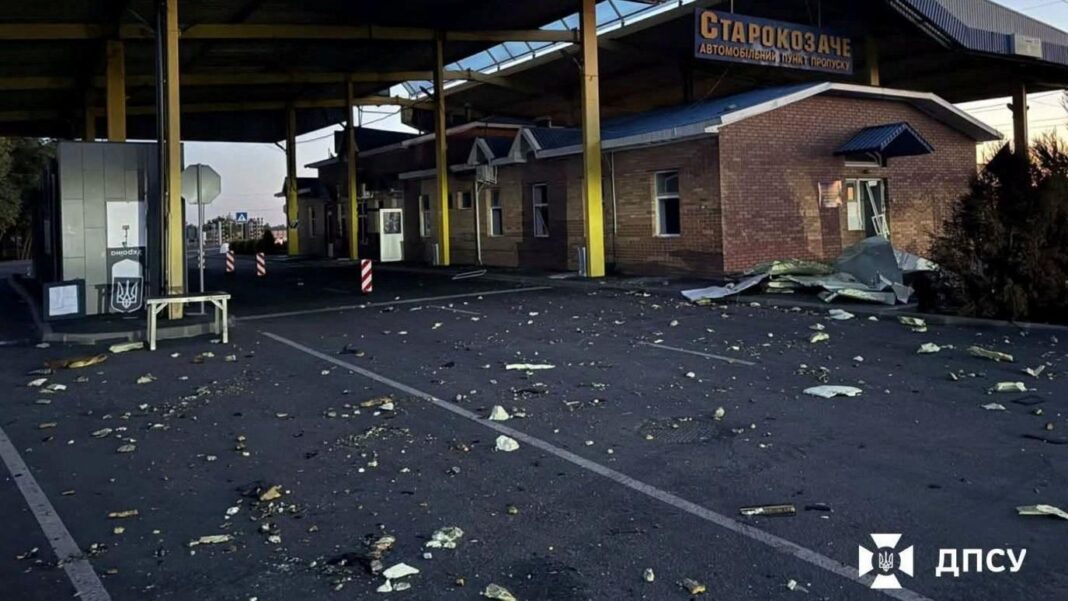 A deserted border checkpoint sits behind a road strewn with debris.