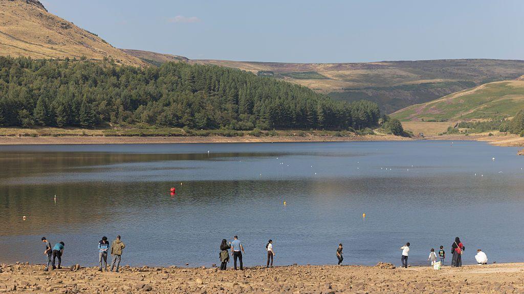 People line the banks of Dove Stone Reservoir as low water levels continue