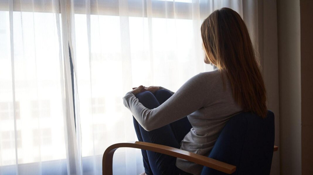 Grooming gangs inquiry expanded to Birmingham and Wales A woman sits with her back to the camera on a chair facing a curtained window.