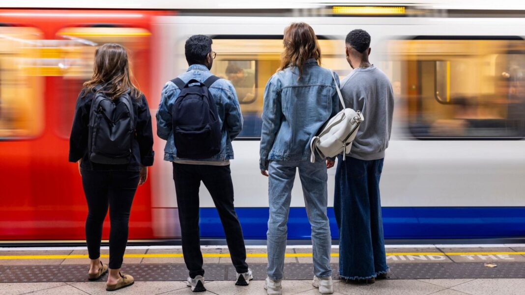 Reported assaults on Britain’s rail services rise by more than a third Four young people stand on a London underground platform facing the tracks as a train arrives.