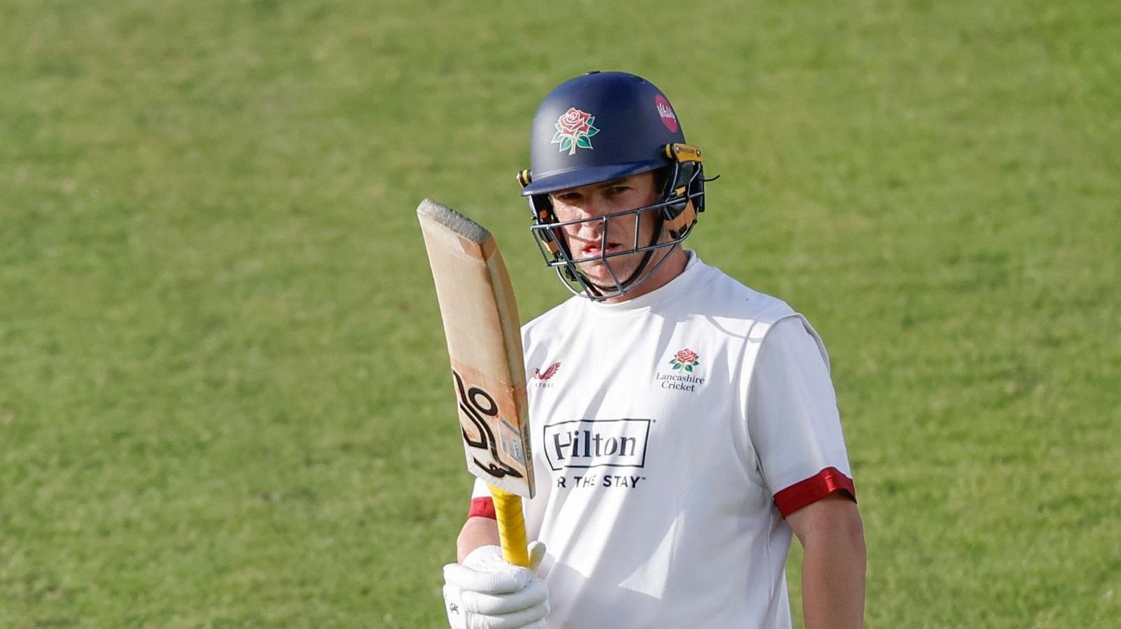 Marcus Harris raises his bat in his right hand upon scoring 50 for Lancashire