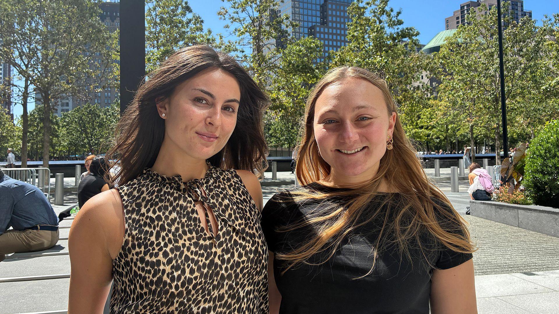 Taylor and Vicky smile while looking at the camera standing outside in an urban environment with buildings and trees in the background.