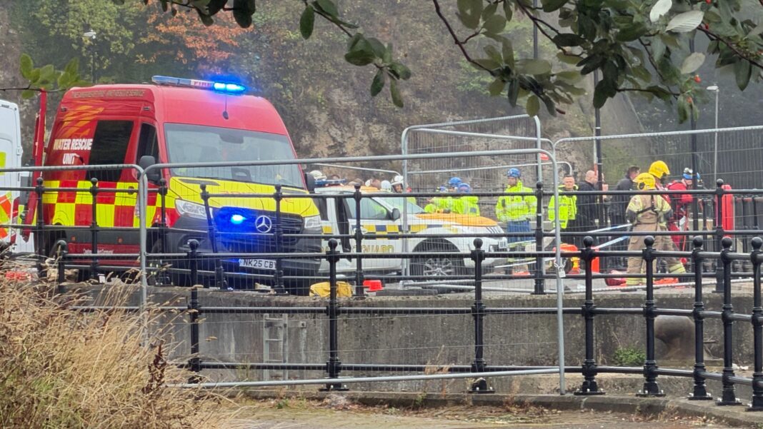 At least a dozen emergency service workers on the river bank in Sunderland, with a water rescue unit van in the foreground. There is temporary fencing around the area. Many of the emergency staff are wearing yellow high-viz jackets and helmets.