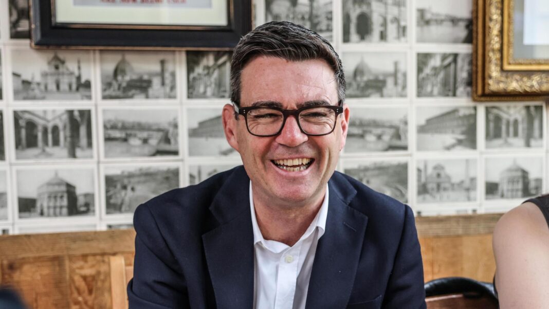 Andy Burnham grinning as he chats to people in a pub