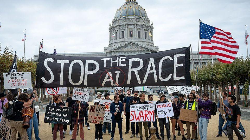 Protesters at an AI demonstration outside City Hall in San Francisco, California. Some in the crowd are holding a large black "Stop the AI race" banner, while others hold placards calling for a pause to AI development.