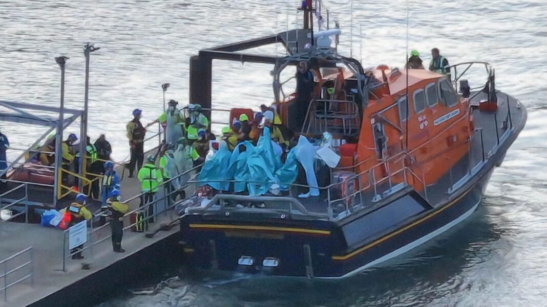 People wrapped in blankets on the back of an RNLI lifeboat moored by a pontoon at Eastney, Portsmouth, on 6.9.26