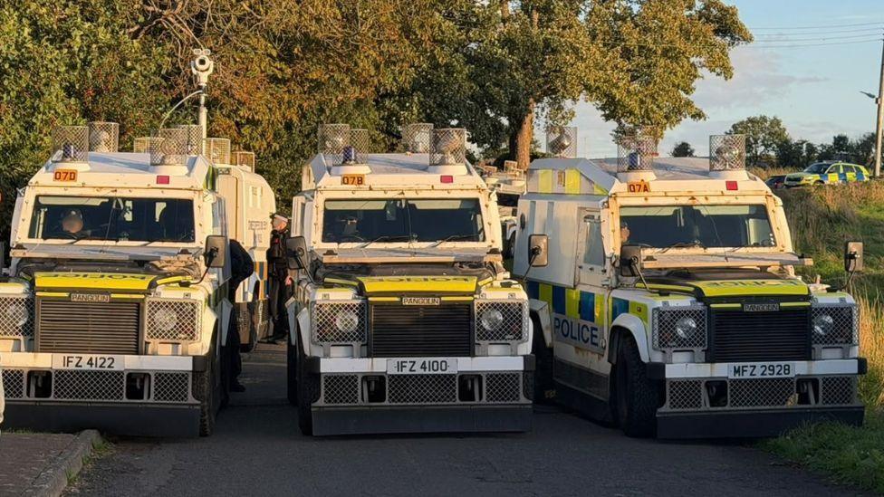 A row of three white police Land Rovers blocking a country lane