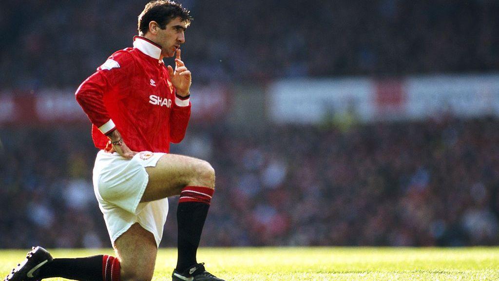 Eric Cantona kneels