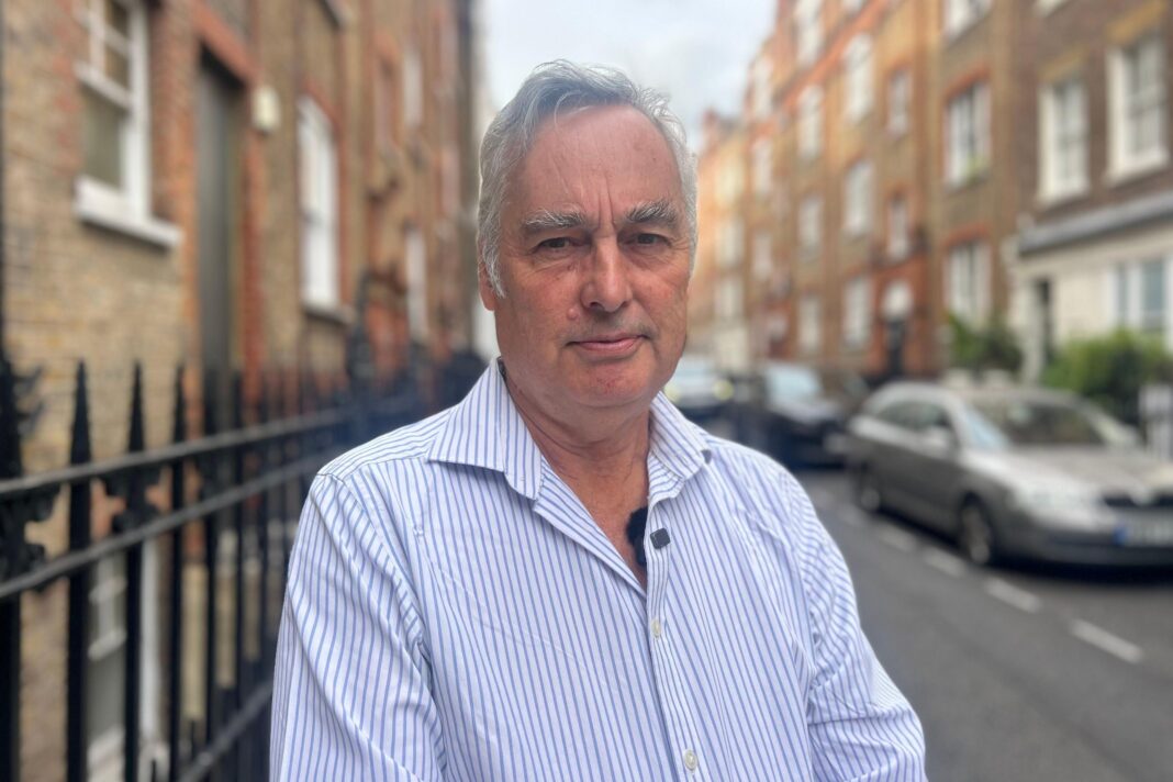 ‘I’ve had no hot water or heating for most of my pregnancy’ Martin Boyd, who is wearing a blue and white striped shirt, stands on a pavement in a street. There are cars and houses behind him.