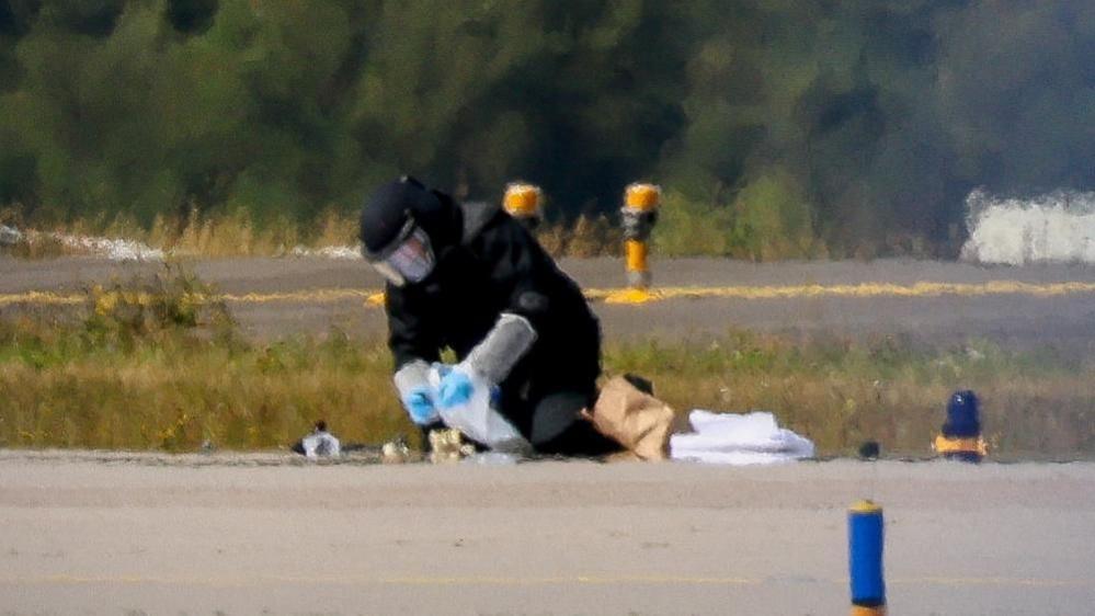 A blurred image of a man defusing a bomb on an airport runway