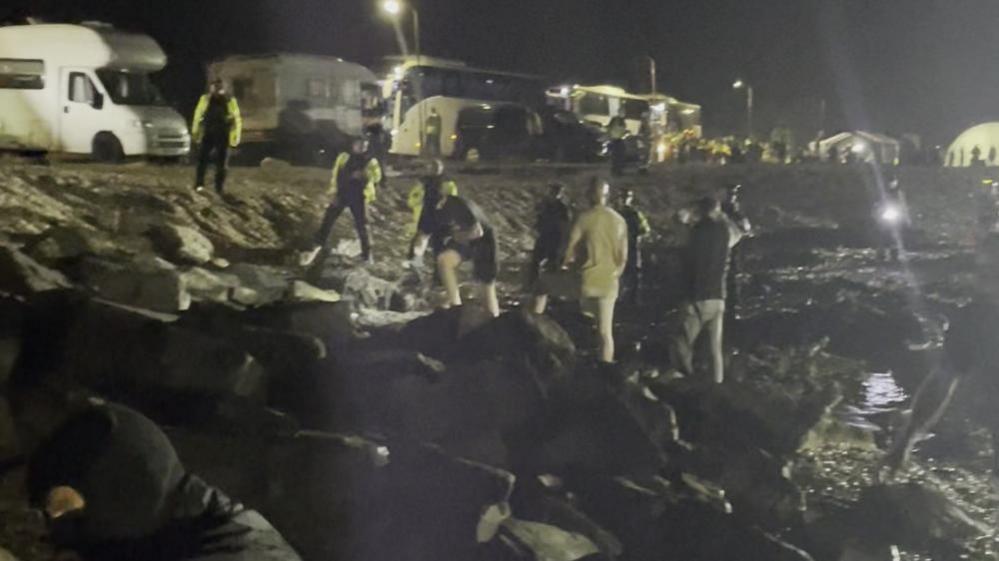 Protesters on the shore with police officers nearby