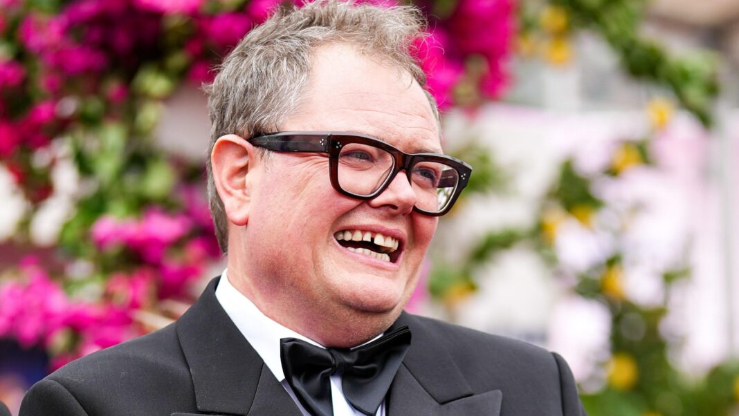 Alan Carr lodges plans to turn castle potting shed into café Comedian Alan Carr in a bow tie and black suit against a blurred background of flowers