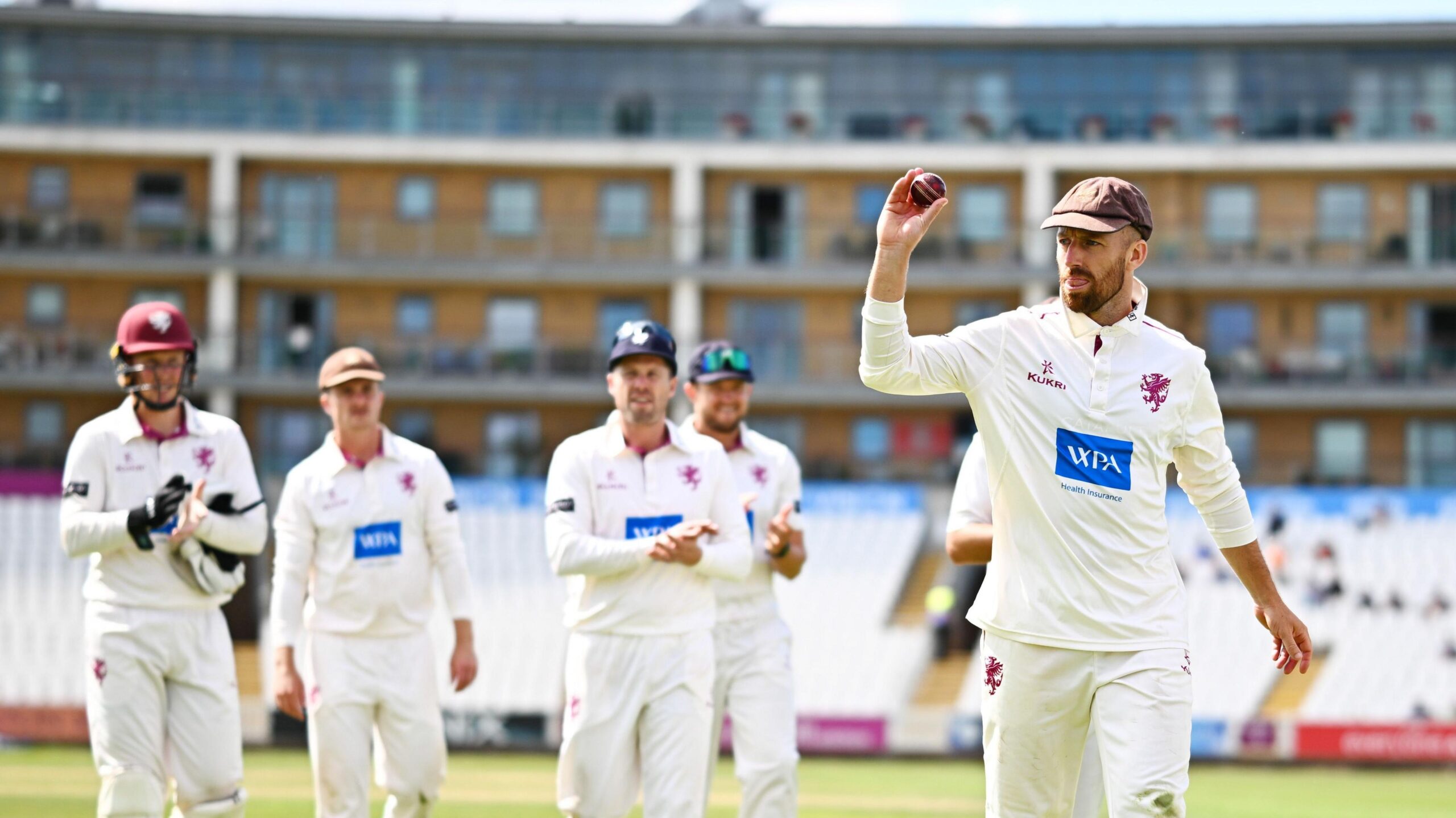 Jack Leach raises the ball to acknowledge the cheers as he leads Somerset off the field after victory