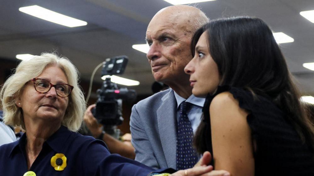 Claudio and Paola Regeni holding the hand of their daughter Irene Regeni as they all watch the trial for Giulio Regeni