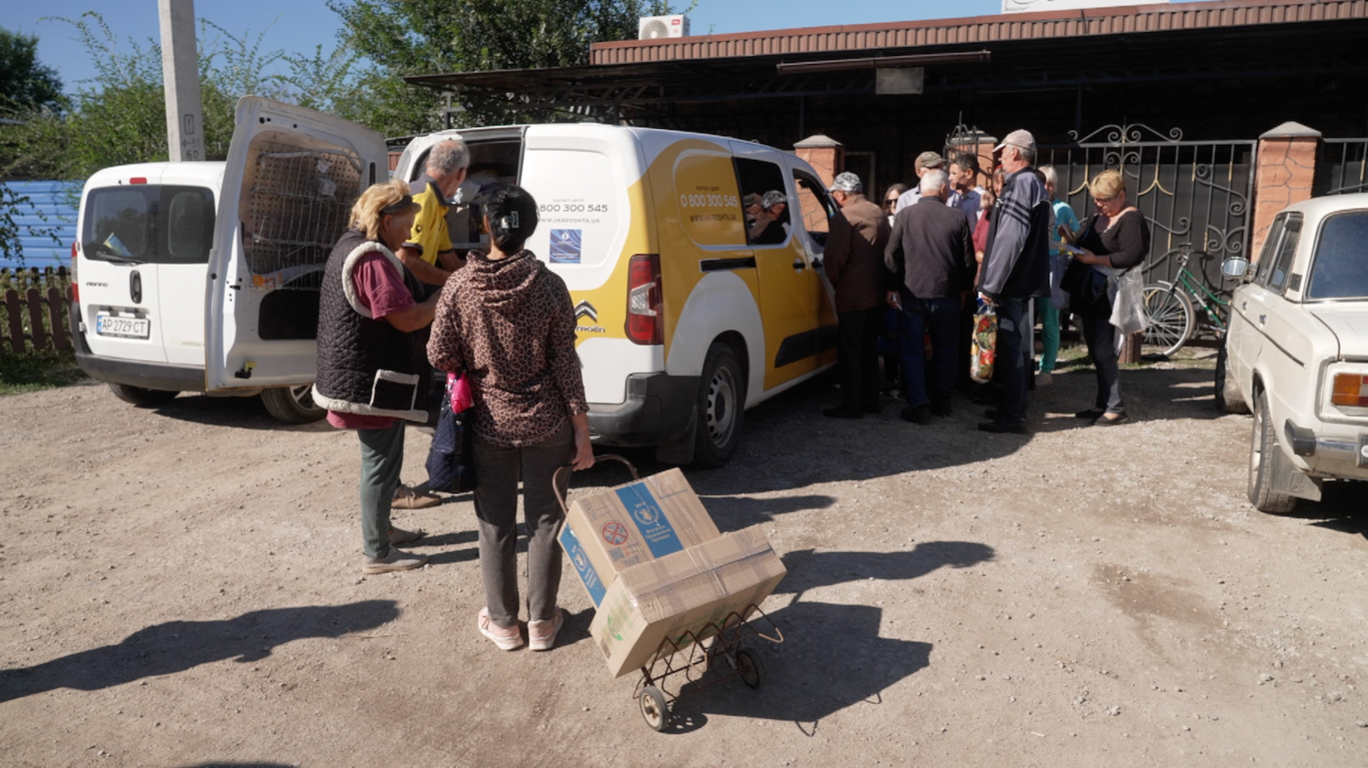 Ukrainians gather around a white and yellow postal van in a town west of Zaporizhzhia