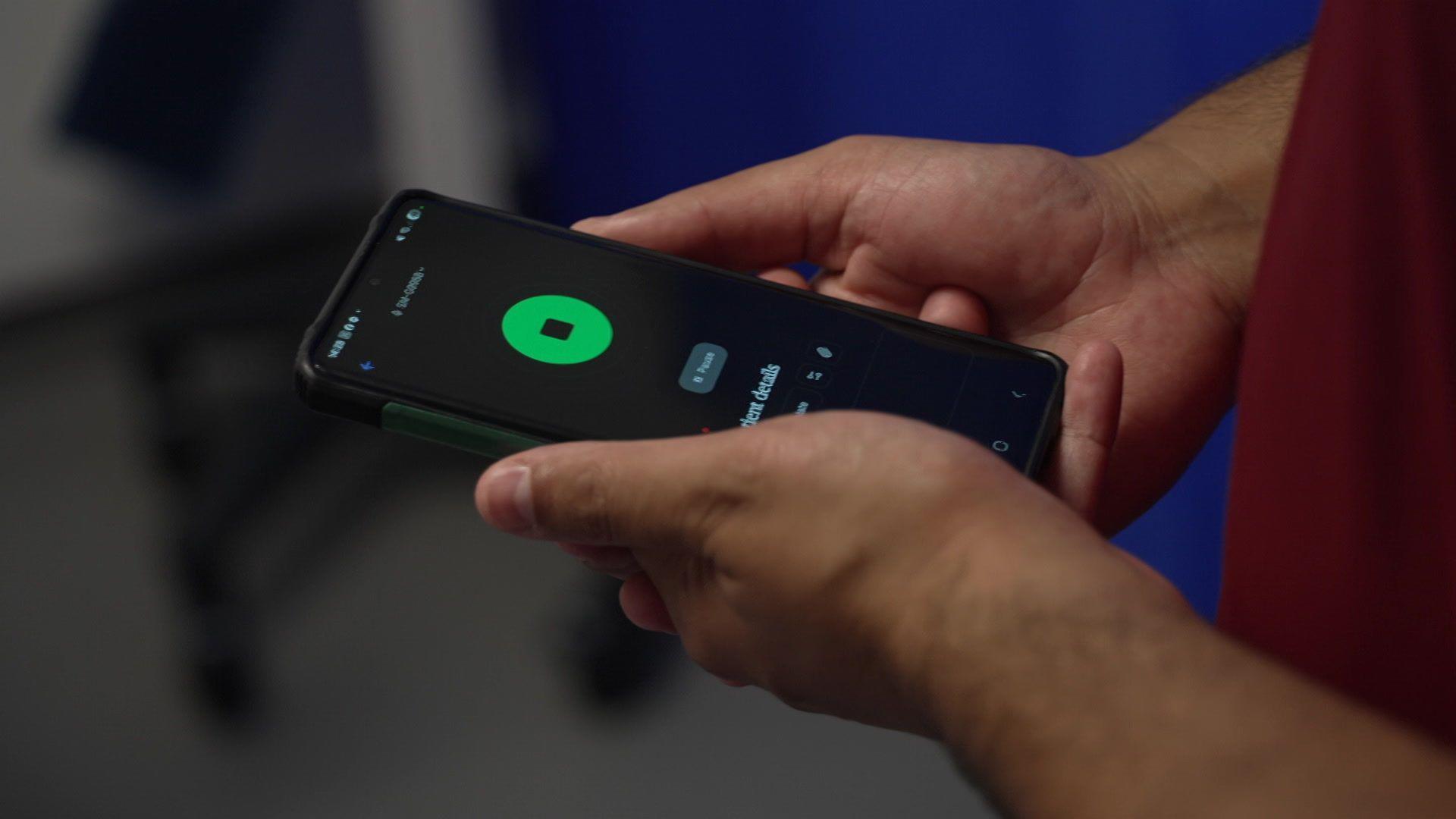 A doctor holding a mobile phone with a recording app open