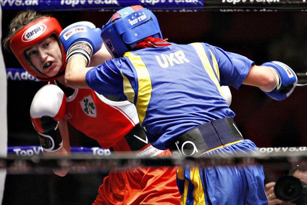 Katie Taylor in red headgear punches evades a punch from her opponent