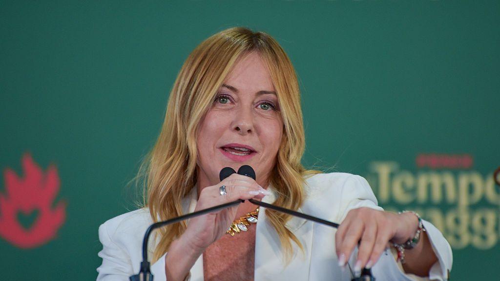 Italian Prime Minister Giorgia Meloni, who has long blonde hair and is wearing a white jacket, speaks into a microphone at an event on 20 September.