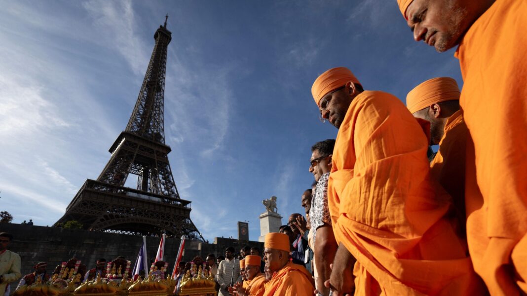 Investigation after female staff at Eiffel Tower replaced by men for religious visit Hindu monks stand in front of the Eiffel Tower wearing traditional orange robes.