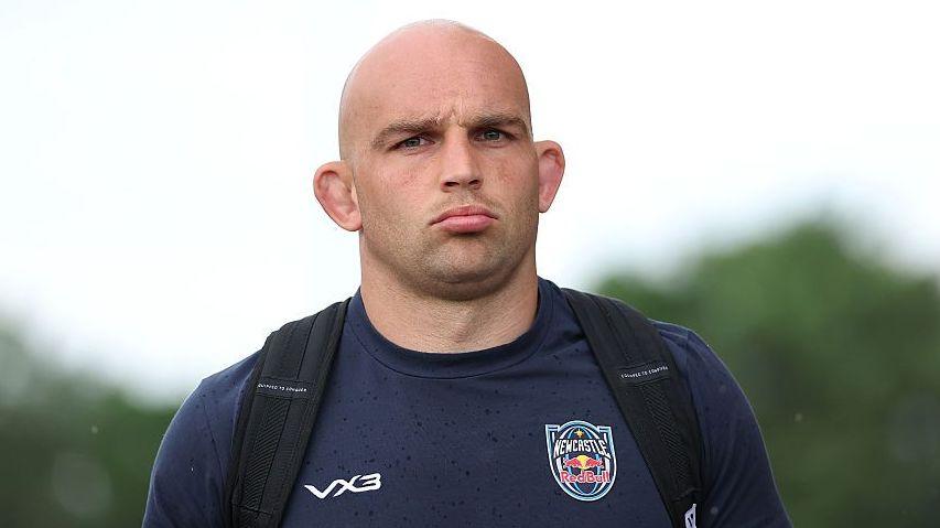 Tom Christie wearing a navy Newcastle Red Bulls t-shirt with a backpack on both shoulders