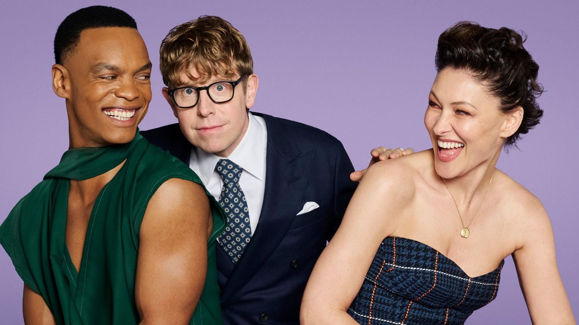 Johannes Radebe, Josh Widdicombe and Emma Willis smiling together in smart, presenting clothes