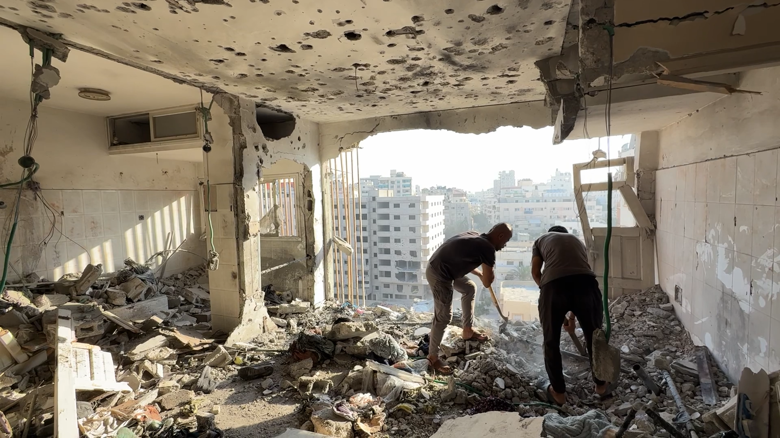 Men assess scene of Israeli strike on high-rise block in Gaza City on 2 August