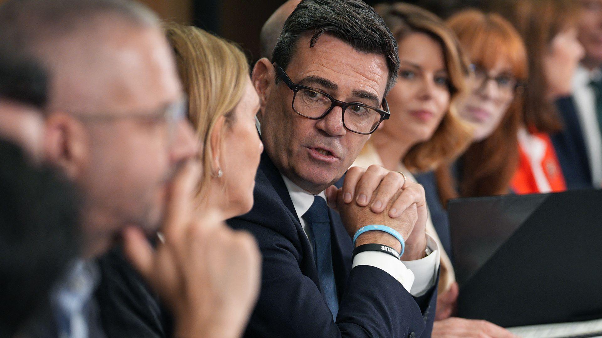 Andy Burnham clasps his hands as he looks towards camera while speaking to others sitting on a long table at a meeting of the National Economic Council in Manchester on 24 July.