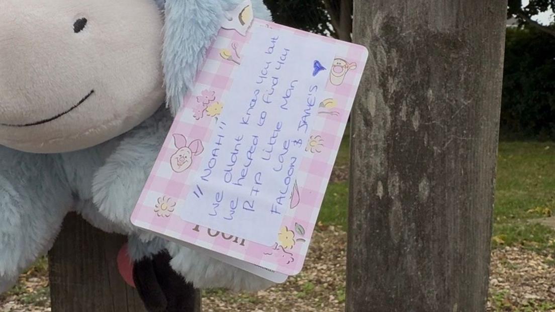 A close up shot of a label on a soft toy where a message has been written. It reads 'Noah we didn't know you but we helped to find you. RIP little man love Faloon and James.