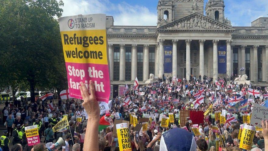 View of anti-racism demonstrators looking towards anti-migration protests with Portsmouth Guildhall in the background