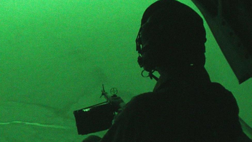 A night-vision view of a soldier sitting in a helicopter