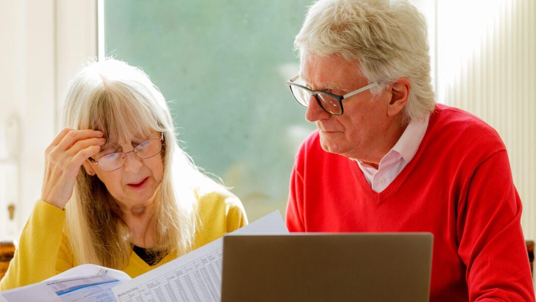 An elderly couple look at financial paperwork