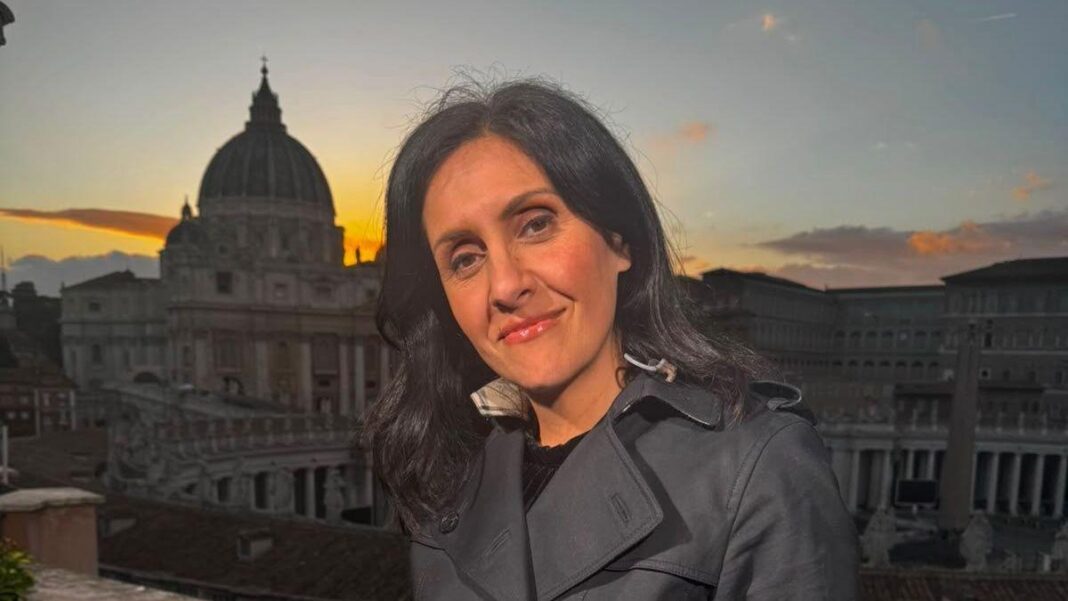 Maryam Moshiri stand in a black coat. The Vatican is in the background