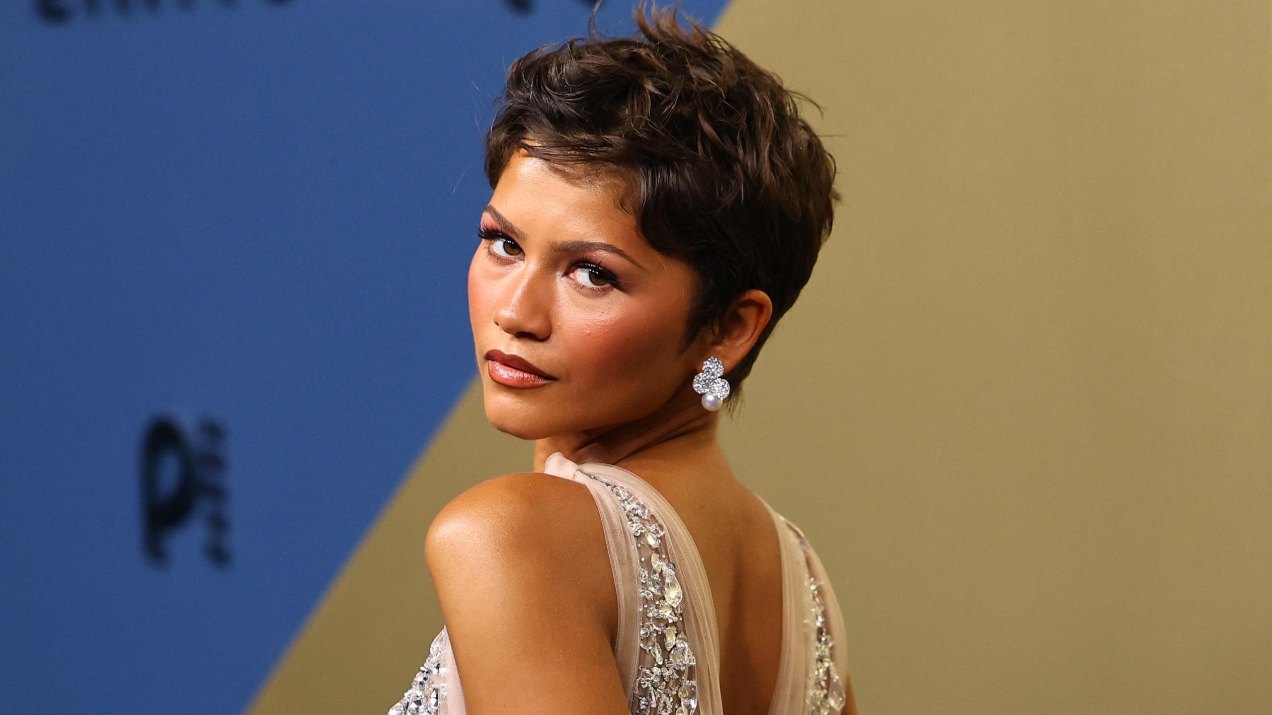 Zendaya in a jewelled dress looking behind her