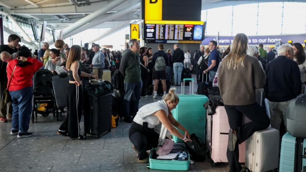 Groups of passengers wait in Heathrow T5 after disruption on Tuesday 8 September