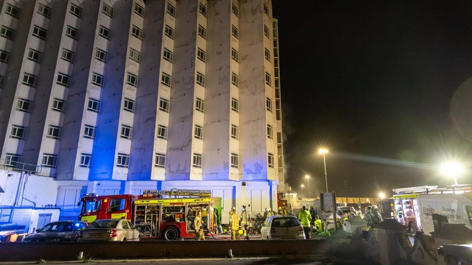 A large building with emergency service vehicles below.