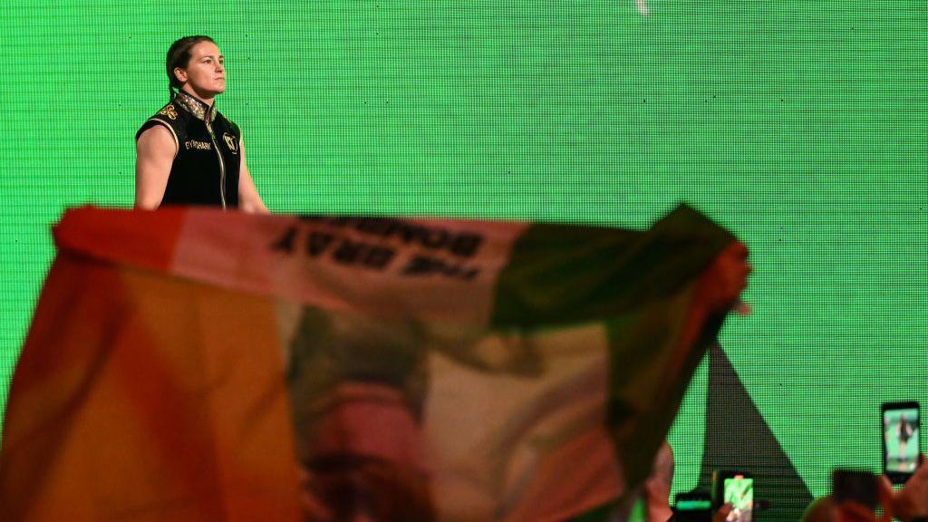 Katie Taylor enters the arena with a massive Irish flag in the crowd