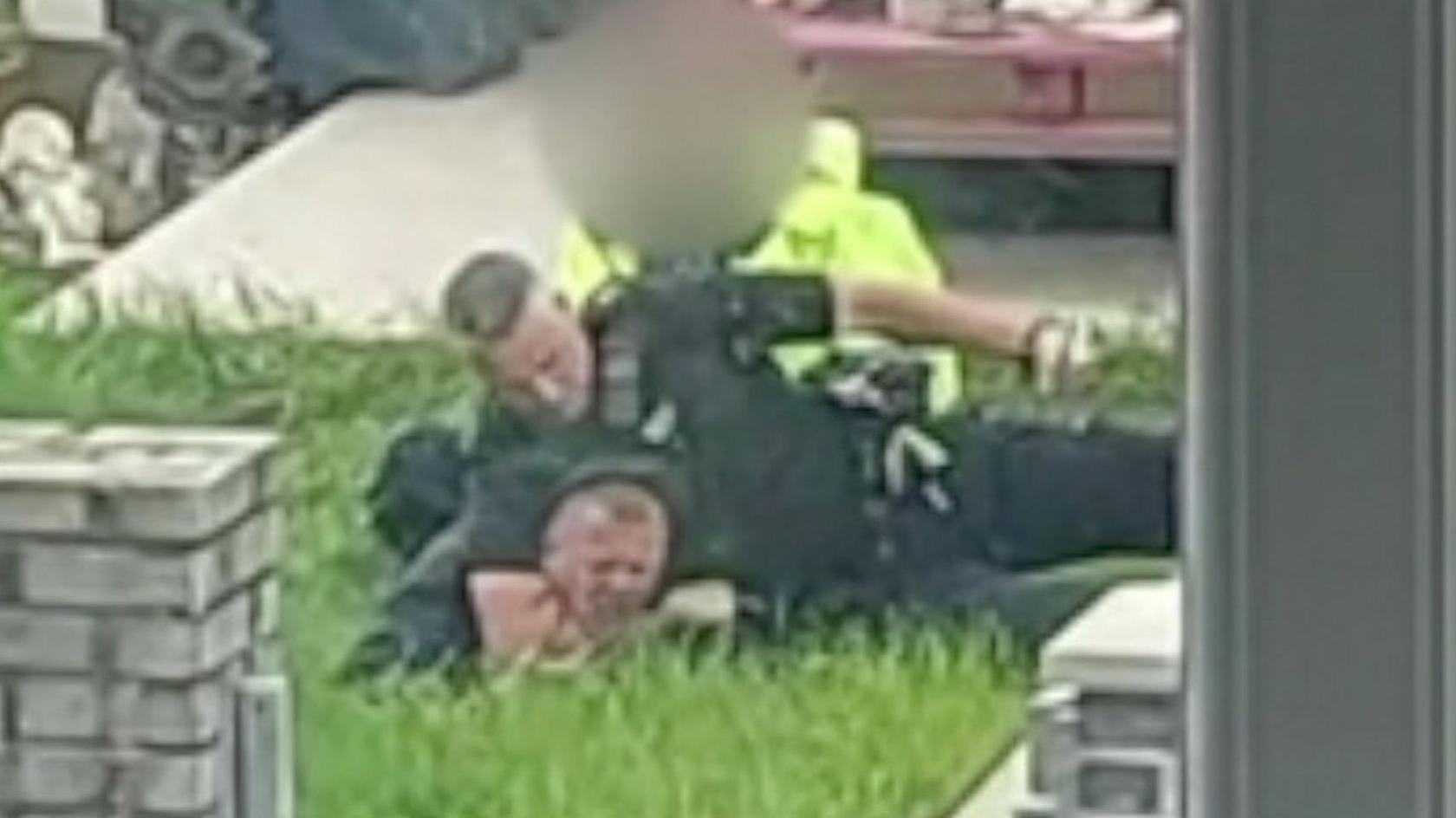 Police officer holding man to the ground in a garden