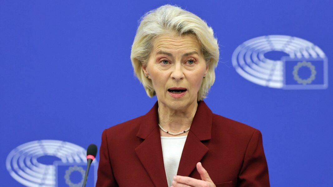 Ursula von der Leyen, who has a short blonde haircut and wears a burgundy blazer with a white top, speaks at a lectern in the European Parliament on Thursday