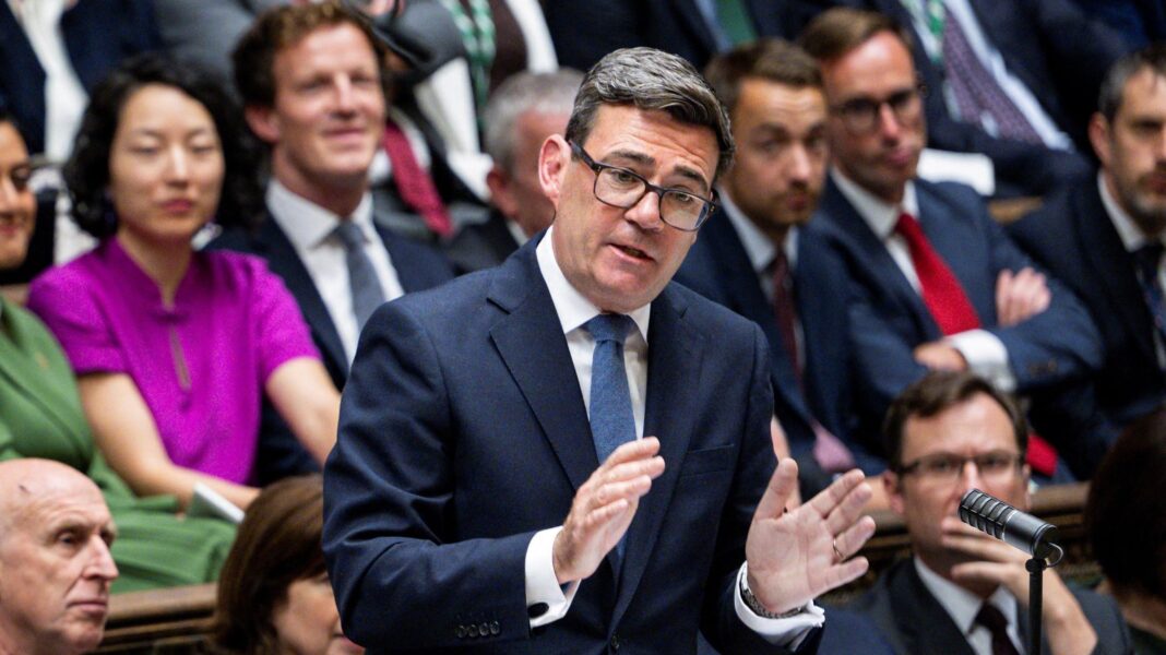 Andy Burnham in the House of Commons at Prime Minister's Questions. He is wearing a dark blue suit, white shirt and blue tie.