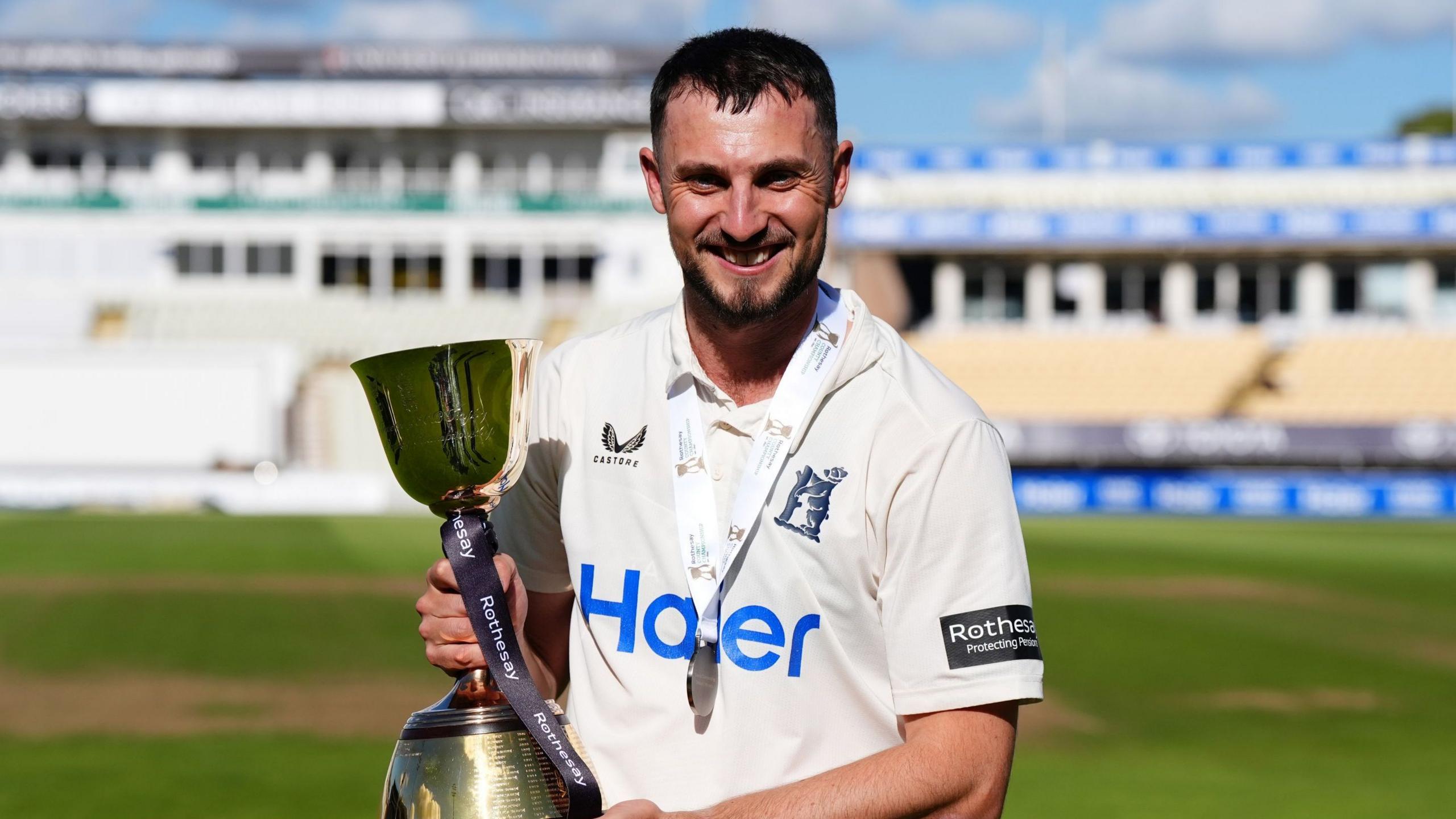 Ed Barnard looking straight ahead and holding the County Championship trophy in his hands