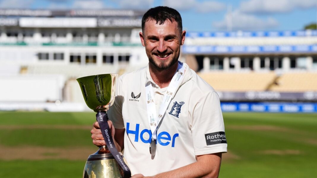 Ed Barnard looking straight ahead and holding the County Championship trophy in his hands